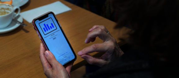 Foto von einem Mobiltelefon, das in der Hand einer Person bedient wird.