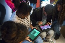 Menschen, die nebeneinander sitzen und ein Tablet auf ihrem Schoß haben.
