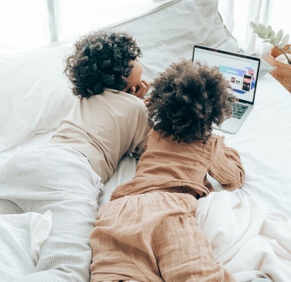 Zwei Kinder, die auf einen Laptop schauen.
