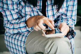 Eine Person, die mit ihren Fingern auf ein Smartphone tippt.