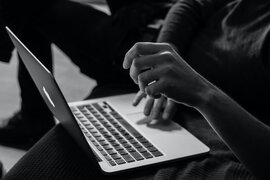 Eine Person, die an einem Laptop sitzt.