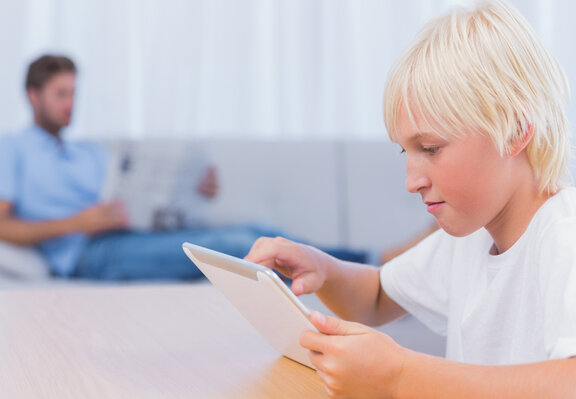 Junge mit Tablet und Vater mit Zeitung  