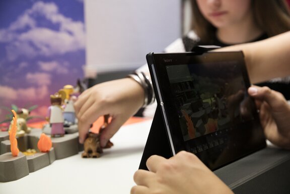 Ein Tablet, das auf einem Tisch steht und mit dem Spielfiguren aufgenommen werden.