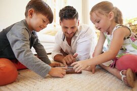 Ein Vater spielt mit seinen Kindern am Tablet.