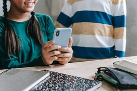 Zwei Kinder, von denen eines ein Smartphone in den Händen hält.
