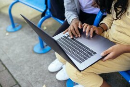 Junge Menschen, die an einem Laptop sitzen.