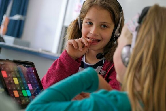 Zwei Mädchen mit Kopfhörern am Tablet  