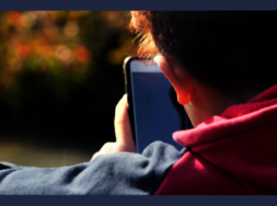Eine Person, die von hinten zu sehen ist und ein Smartphon ein den Händen hält.