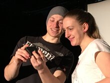 Zwei Personen, die auf ein Smartphone schauen, welches eine Person in den Händen hält.
