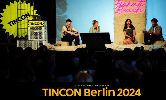 Menschen, die auf einer Bühne sitzen und miteinander im Gespräch sind