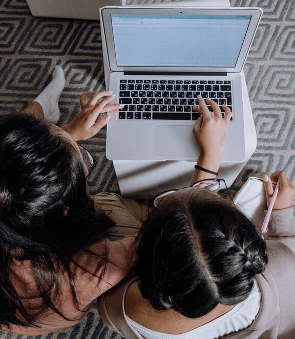 Zwei Menschen, die an einem Laptop sitzen.