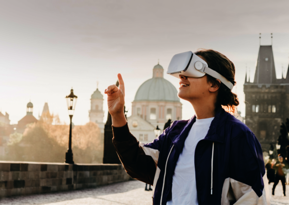 Eine Person, die eine VR-Brille trägt. Hinter ihr ist eine Stadt zu sehen.