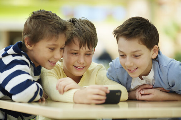 Kinder, die auf ein Smartphone schauen  