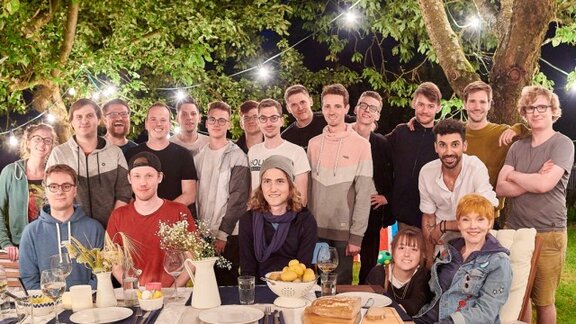 Eine Gruppe von Menschen, die nebeneinander stehen und nach vorne schauen.