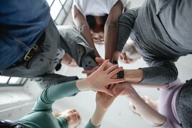 Menschen, die ihre Hände in einem Kreis aufeinanderhalten.