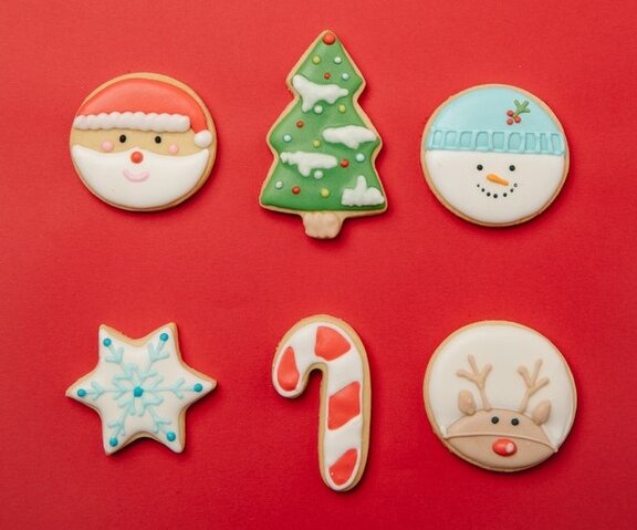 Plätzchen, auf denen ein Weihnachtsmanngesicht, ein Gesicht eines Schneemannes, ein Gesicht eines Rentiers abgebildet sind. Zudem gibt es noch ein Plätzchen in Form eines Sterns und in Form eines Hakens.