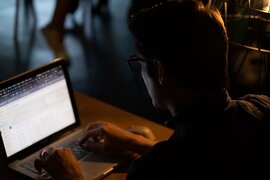 Eine Person, die an einem Laptop sitzt.