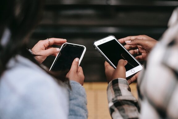 Zwei Personen, die beide ein Smartphone in ihren Händen halten.