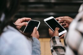 Zwei Personen, die beide ein Smartphone in ihren Händen halten.