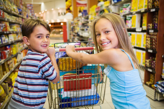 Zwei Kinder schieben einen Einkaufskorb  