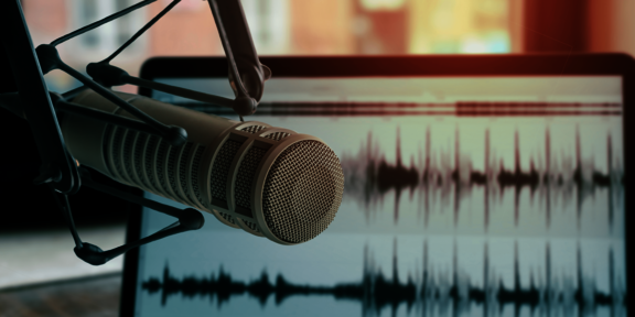 Aufnahmemirkofon vor Bildschirm mit Tonspuren