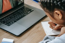 Ein Mädchen, dass auf einen Blog schreibt und vor einem Laptop sitzt.
