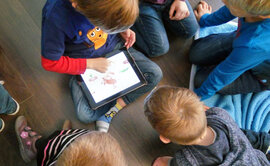 Kinder, die an einem Tablet sitzen.