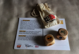 Eine Postkarte, auf der ein kleiner Stoffbeutel sowie zwei Würfel liegen.