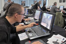 Erwachsene, die am Laptop sitzen und ein digitales Spiel spielen.