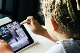 Ein Kind, das auf einem Tablet etwas spielt.