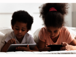 Zwei Kinder, die jeweils ein Tablet vor sich liegen haben, mit dem sie sich beschäftigen.