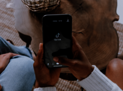 Eine Person, die ein Smartphone in den Händne hält, auf dem "TikTok" steht.
