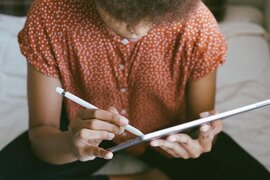 Eine Person, die mit einem Stift auf einem Tablet schreibt.