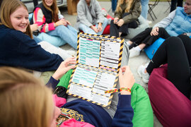 Menschen, die auf dem Boden sitzen und sich ein Programmplan anschauen.