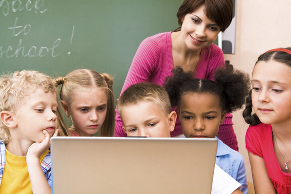 Eine Lehrerin mit Schülern am Laptop  