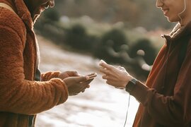 Zwei junge Menschen, die jeweils ein Smartphone in den Händen halten.