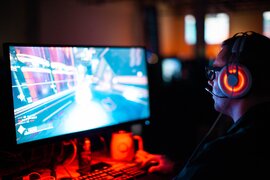 Eine Person, die Kopfhörer aufhat und ein Spiel am PC spielt.