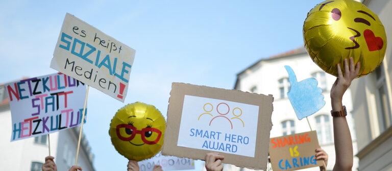 Menschen halten Luftballons und Demonstrations-Schilder in die Luft für mehr soziales Engagement im Netz