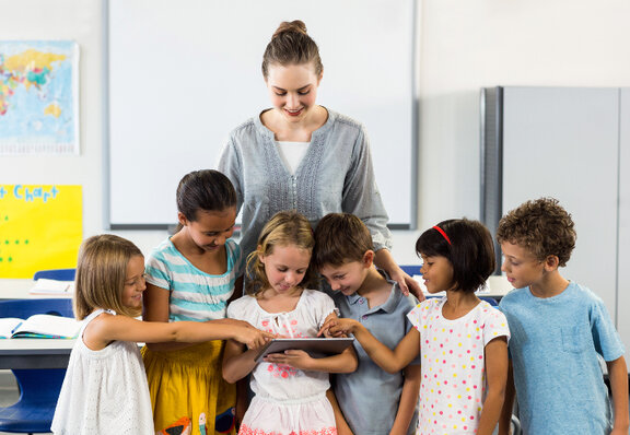 Frau mit Tablet und Kindern in der Schule