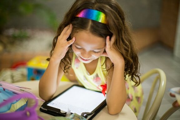 Ein Kind, welches auf ein Tablet schaut.  