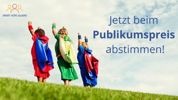 Kinder im Superheldenkostüm stehen neben dem Schriftzug "Jetzt beim Publikumspreis abstimmen!"  