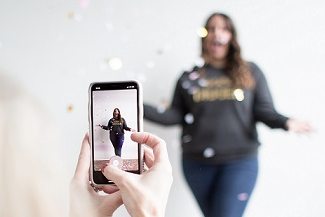 Ein Mädchen wird von einem anderen Mädchen mit dem Smartphone aufgenommen.