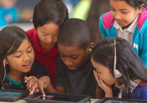 Kinder, die auf ein Tablet schauen, mit dem sie beschäftigt sind.