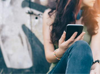 Eine Person, die ein Smartphone in der Hand hält und zur Seite schaut.