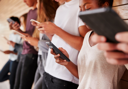 Menschen, die nebeneinander stehen und alle ein Smartphone in den Händen haben, auf das sie schauen.