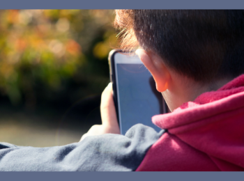 Eine Person, die von hinten zu sehen ist und ein Smartphon ein den Händen hält.