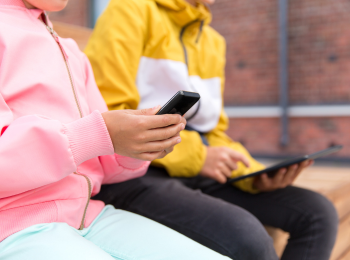 Kinder, die ein Smartphone und ein Tablet in den Händen halten.